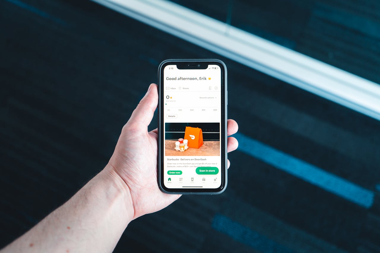 Hand holding smartphone with food delivery app on screen in bright setting.