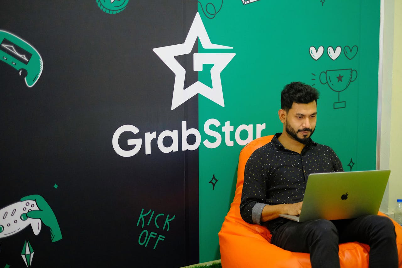 Young man sitting on a bean bag using a laptop in GrabStar office.